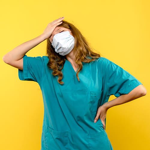 Pflegefachkraft mit Maske wirkt erschöpft – Burnout in der Pflege.